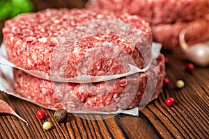 Raw ground beef meat hamburger patties on paper, dry pepper