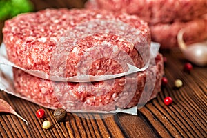 Raw ground beef meat hamburger patties on paper, dry pepper photo