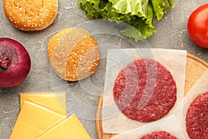 Raw Ground beef meat steak cutlets and burger ingredients on grey table