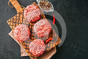 Raw ground meat beef burgers on a wooden board.