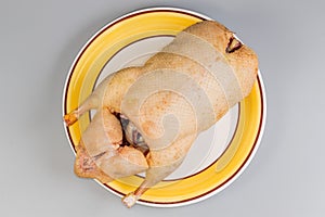 Raw carcass of domestic duck on yellow dish, top view photo