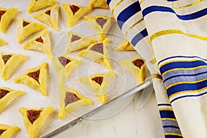 Raw hamantaschen cookies on baking tray with tallit