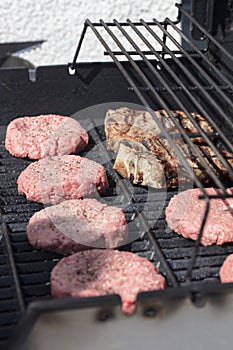 Raw hamburgers being cooked on the grill
