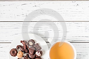 Raw handmade chocolate candies, cup of tea on white wooden table