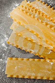 Raw hard homemade fluted lasagna sheets in flour close-up. real life atmosphere. homemade pasta made from durum wheat.