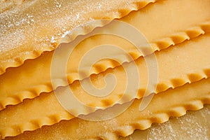 Raw hard homemade fluted lasagna sheets in flour close-up. real life atmosphere. homemade pasta made from durum wheat.