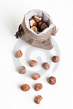 Raw hazelnuts on white background and jute drawstring pouches bag