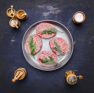 Raw homemade burgers Beef, lined inside vintage pan with spices and herbs on blue rustic wooden background top view