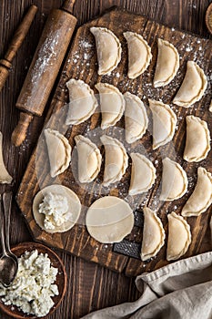Raw homemade cottage cheese dumplings on wooden background