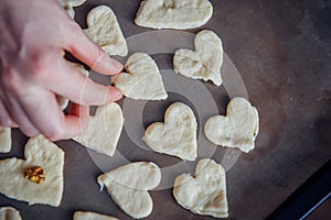 Raw homemade heart-shaped cookies on a baking sheet. Concept of fresh pastry, surprise for Valentine`s day