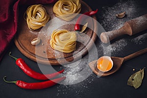 Raw homemade pasta with flour and spices on the rustic background.