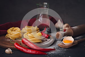 Raw homemade pasta with flour and spices on the rustic background.