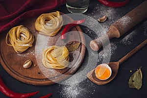 Raw homemade pasta with flour and spices on the rustic background.