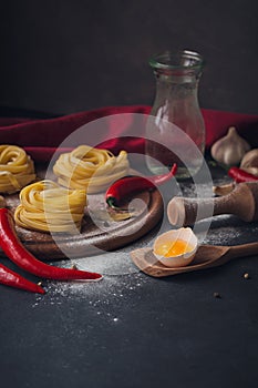 Raw homemade pasta with flour and spices on the rustic background.