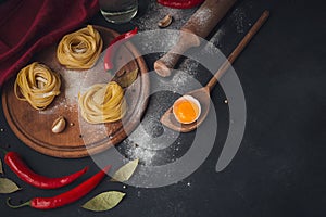 Raw homemade pasta with flour and spices on the rustic background.