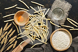 Raw homemade pasta and ingredients and ingredients for cooking pasta on a dark background. Top view, flat lay
