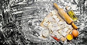 Raw homemade ravioli with egg, flour and a rolling pin.