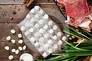 Raw homemade Russian dumplings with meat beef and onion jusai on a board with flour on a dark wooden background.