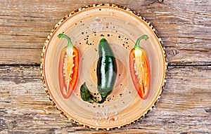 Raw hot green Mexican jalapeno peppers on a ceramic platter. Traditional Spanish tapas on an old wooden table. Flat top view.