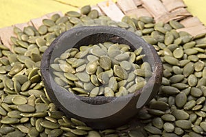 Raw hulled pumpkin seeds in primtive bowl