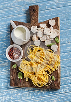 Raw ingredients for cooking pasta with mushroom cream sauce - pasta, mushrooms, cream, spices.