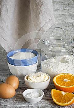 Raw ingredients - flour, eggs, butter, sugar, orange - to cook orange cake. Ingredients for baking.
