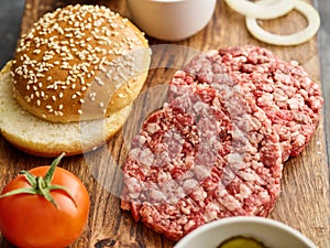 The raw ingredients for the homemade burger. Burger patties. Raw mince meat cutlet, ground beef and pork with bun. Grey background