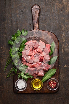 Crudo composizione carne in umido. maiale cubi olio  sale un fresco pepe sul vecchio rurale piatto sul buio di legno 