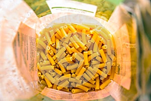 Raw italian macaroni pasta inside clear packaging