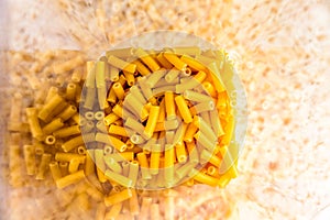 Raw italian macaroni pasta inside clear storage container