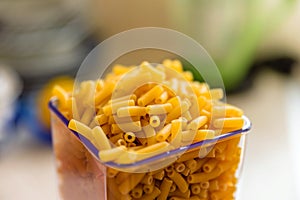 Raw italian macaroni pasta inside clear storage container