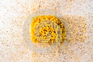 Raw italian macaroni pasta inside clear storage container