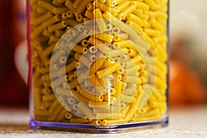 Raw italian macaroni pasta inside clear storage container