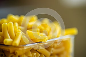 Raw italian macaroni pasta inside clear storage container