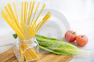 Raw Italian spaghetti in the glass jar and ingredients for cooking.