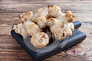 Raw Jerusalem artichoke, topinambur tubers on a rustic wooden background. Copy space