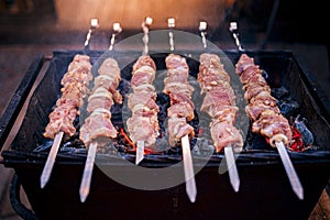 Raw kebab cooking on metal skewer. Roasted meat cooked at barbecue. Traditional eastern dish, shish kebab. Grill on