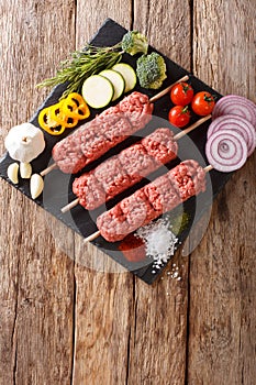 raw kebab of ground beef with ingredients and vegetables close-up. Vertical top view from above