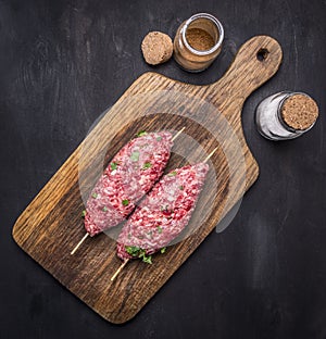 Raw kebab skewers on a chopping board with spices on wooden rustic background top view close up