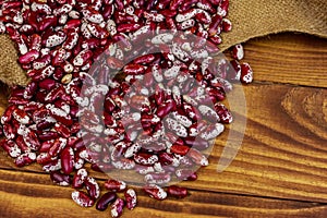 Raw kidney beans on burlap on wooden table