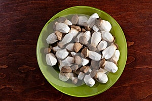 Raw king oyster mushrooms, Pleurotus eryngii, on a green plate standing on a wooden board