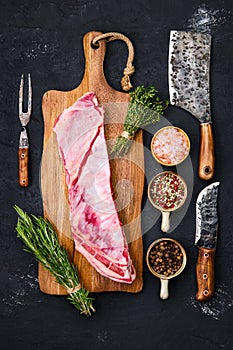 Raw lamb breast and flap on wooden cutting board with herbs and seasoning