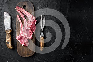 Raw lamb chops or mutton cuts, on black dark stone table background, top view flat lay, with copy space for text