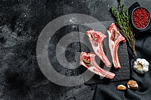 Raw lamb chops, Rack of Lamb with rosemary and spices. Organic meat steak. Black background. Top view. Copy space