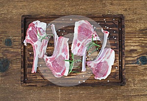 Raw lamb chops. Rack of Lamb with rosemary and spices on rustic chopping board over old wooden background.