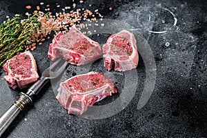 Raw lamb loin steaks, chops cutlets on kitchen table. Black background. Top view. Copy space