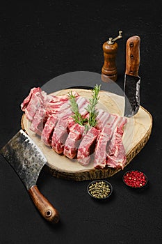 Raw lamb rib roast on wooden slab and butcher cleaver