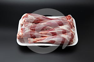 Raw lamb shanks in a white styrofoam box isolated on black background with copy space for text