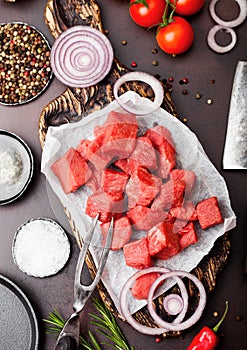 Raw lean diced casserole beef pork steak with vintage meat hatchet and fork on brown background. Salt and pepper with fresh