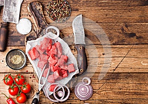Raw lean diced casserole beef pork steak with vintage meat hatchet and knife on wooden background. Salt and pepper with fresh